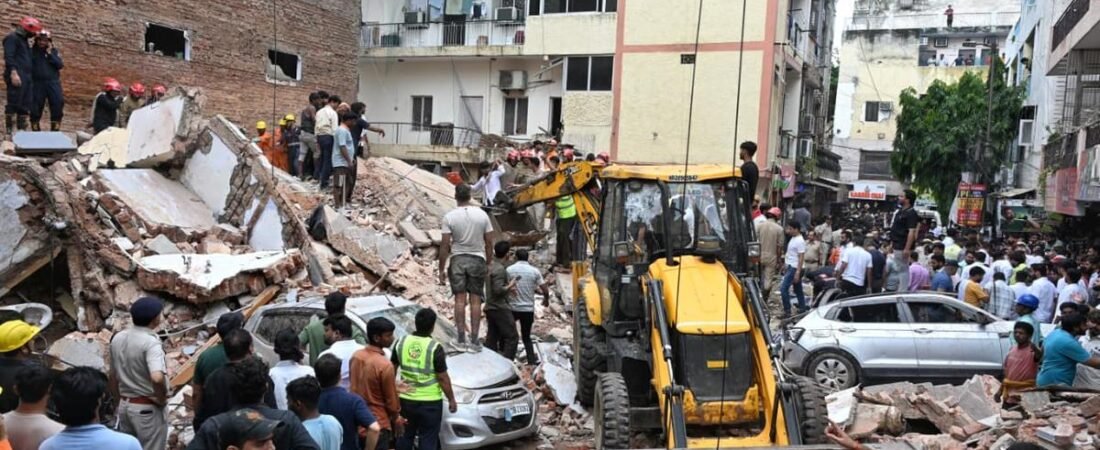 Rescue workers and emergency personnel search through debris after a building collapse in Satya Niketan, Delhi